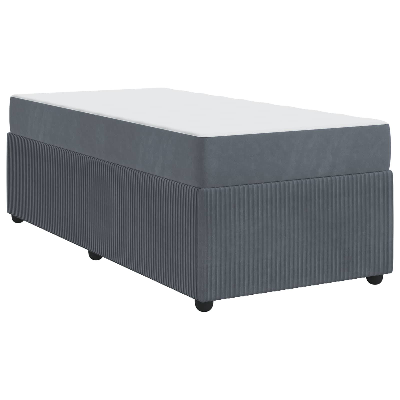 Ein grau gepolsterter Hocker mit einer weißen Oberfläche, in einem schrägen Winkel präsentiert, der seine rechteckige Form und gerippte Stoffstruktur zeigt.