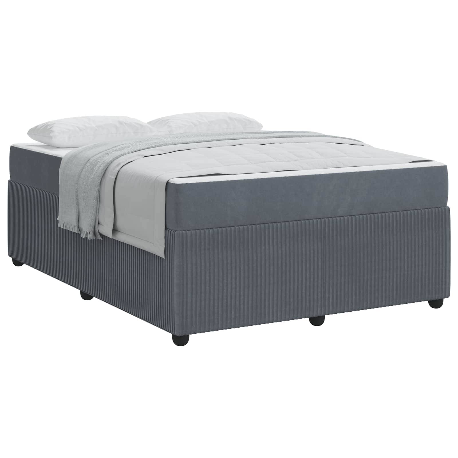 Ein grau gepolstertes Bett mit einer hellgrauen Bettdecke und zwei weißen Kissen. Das Bett hat ein schlichtes, modernes Design und steht auf Rollen.