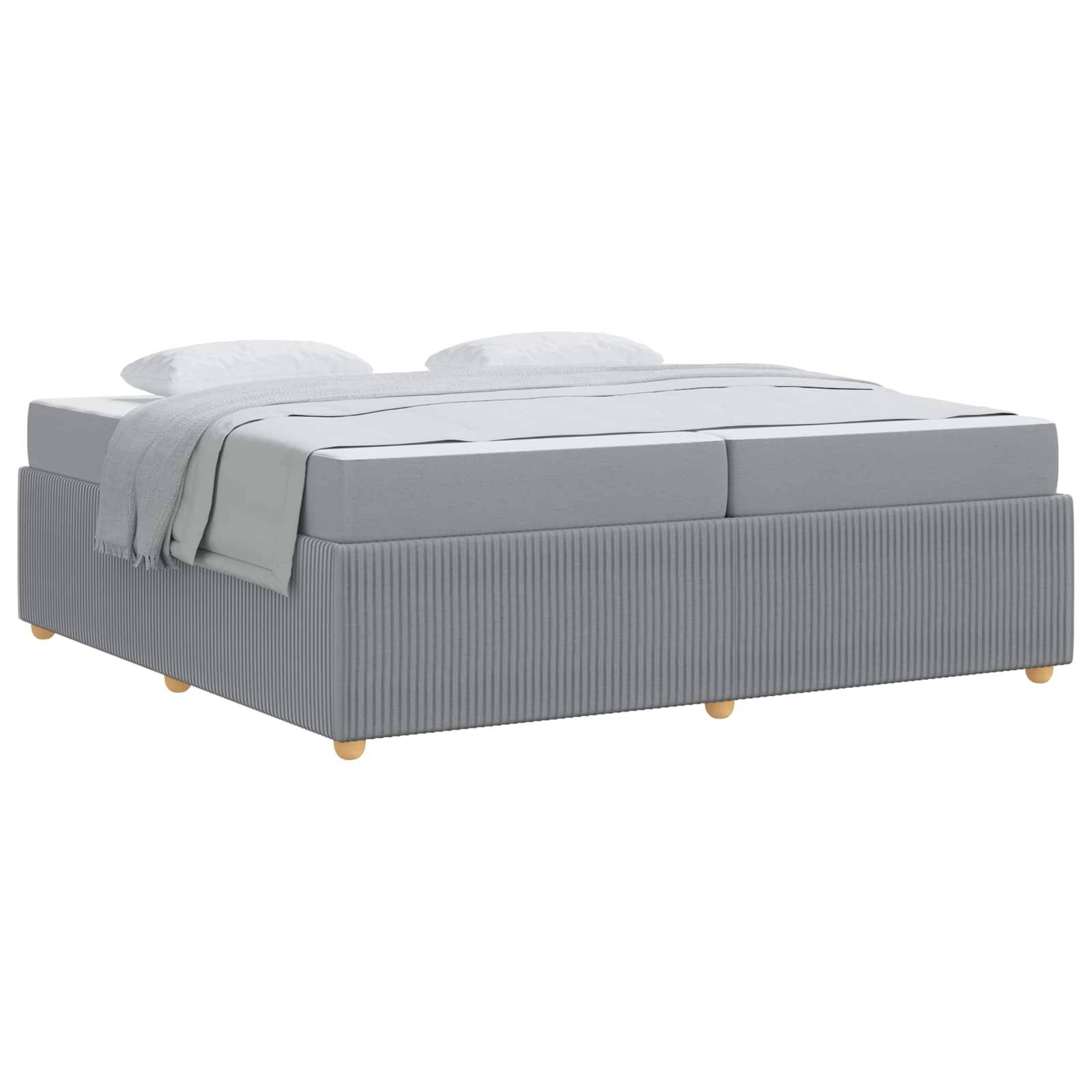 Ein grau gepolstertes Bett mit hellen Holzbeinen, bedeckt mit weißer Bettwäsche und zwei passenden Kissen, präsentiert vor einem schlichten Hintergrund.