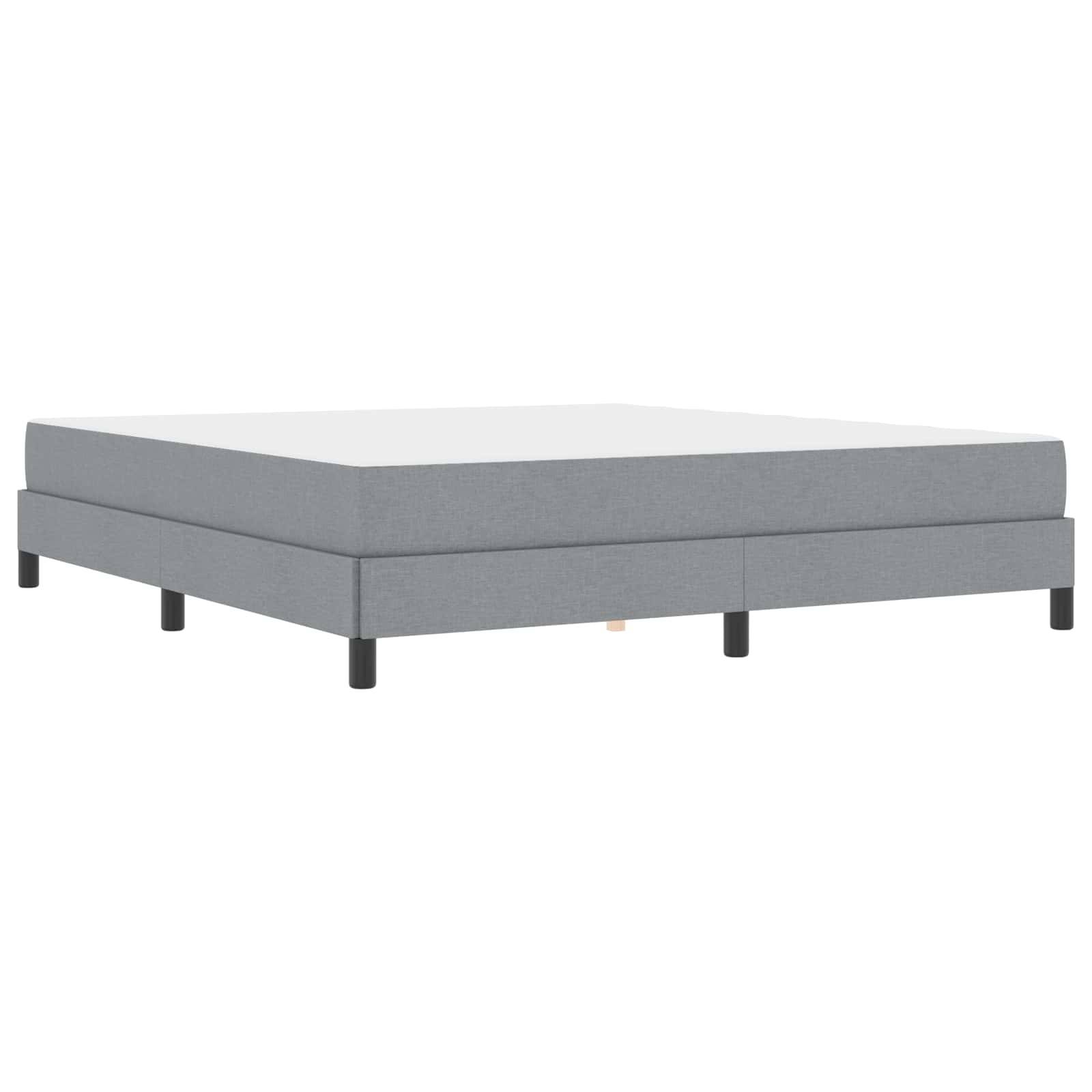 Grau gepolstertes Plattformbett mit schwarzen Beinen, von der Seite betrachtet. Schlichtes und modernes Design mit rechteckiger Form.