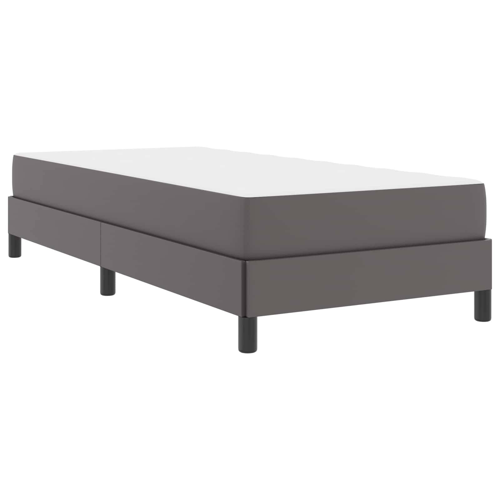 Ein graues Plattformbett mit schlichtem Design, das eine niedrige rechteckige Struktur und vier schwarze Beine aufweist, vor einem weißen Hintergrund positioniert.