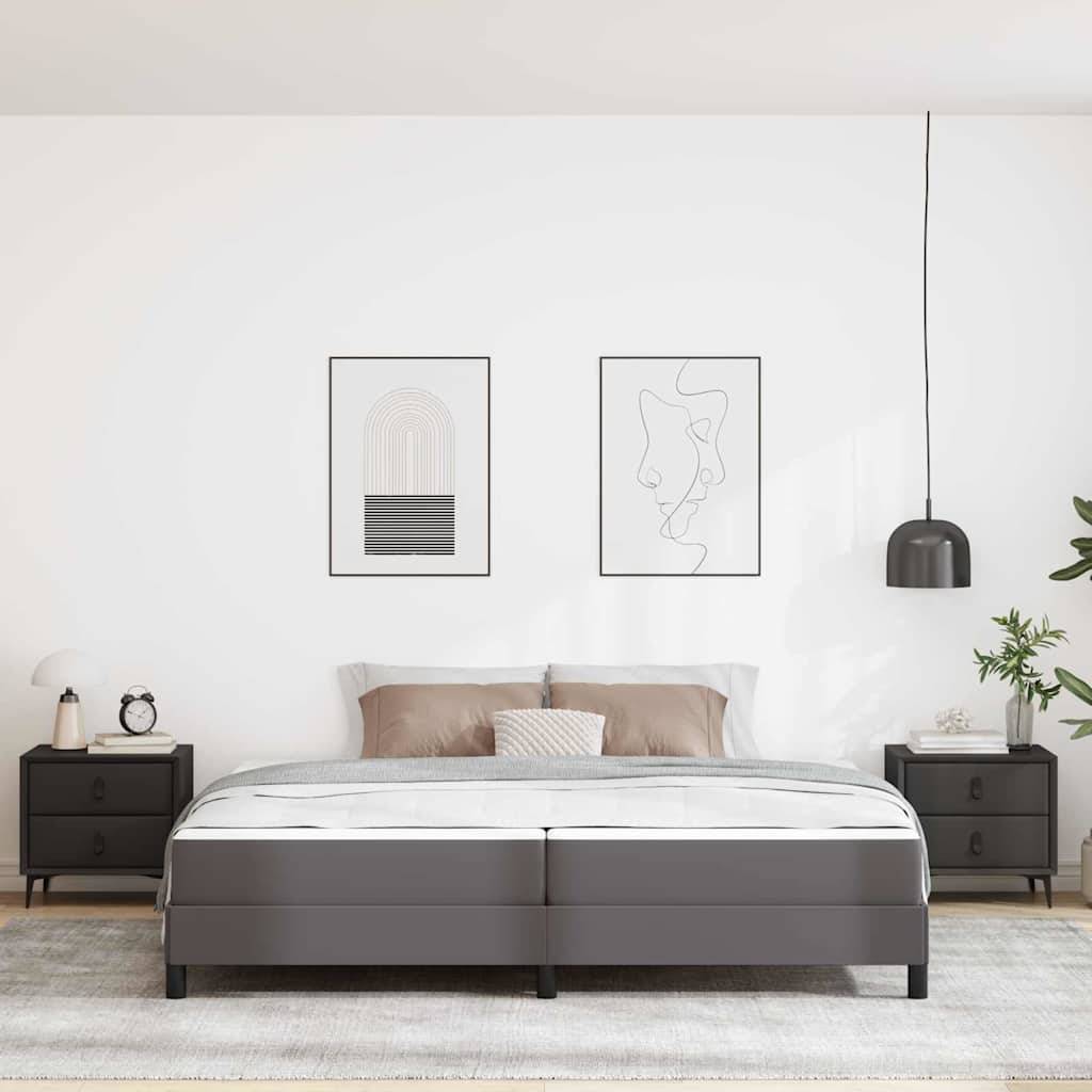 Ein modernes Schlafzimmer mit einem Bett, das mit grauer Bettwäsche bezogen ist, zwei gerahmten abstrakten Kunstwerken an der Wand darüber und passenden schwarzen Nachttischen und Lampen.