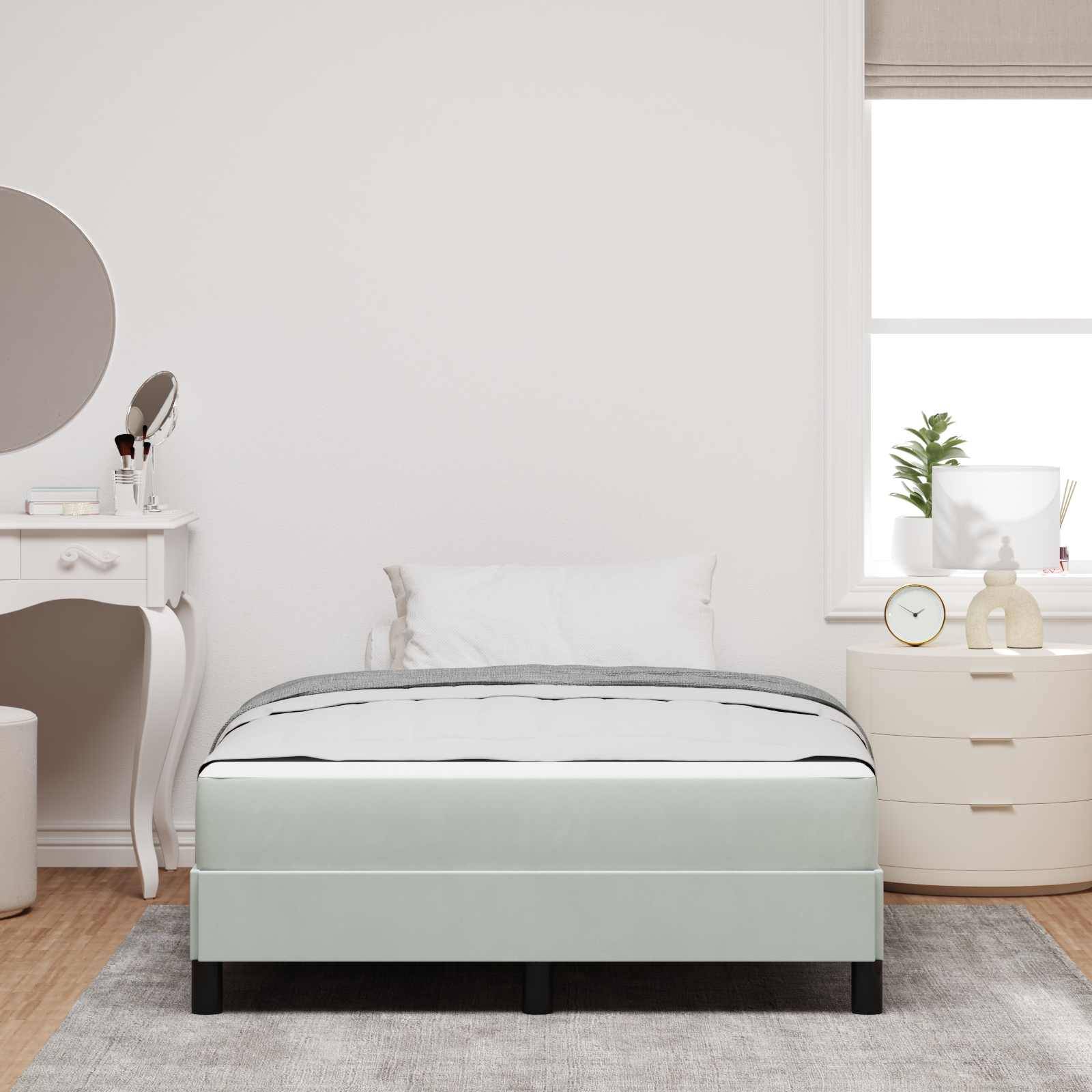 Ein modernes Schlafzimmer mit einem grauen Bett, weißem Kissen und einem Frisiertisch auf der linken Seite. Weiches Tageslicht fällt durch ein Fenster herein und beleuchtet den Raum.