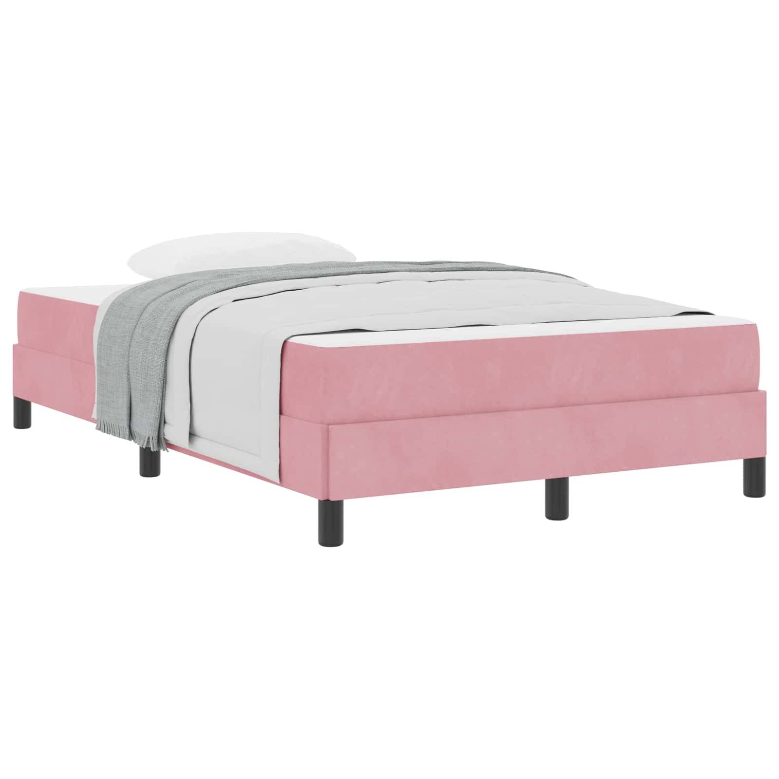 Ein rosa gepolstertes Bett mit einer weißen Matratze, weißem Kissen und einer grauen Decke, die über die Seite hängt. Das Bett hat schwarze Beine.