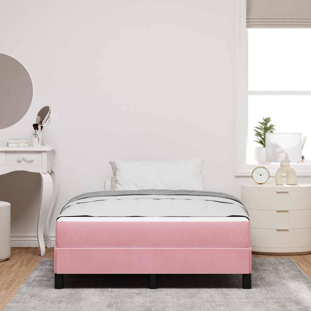 Ein Schlafzimmer mit einem pinken Bett, weißen Kissen, einem runden Nachttisch mit einer Pflanze und einer Kommode mit rundem Spiegel vor einer blassen Wand.