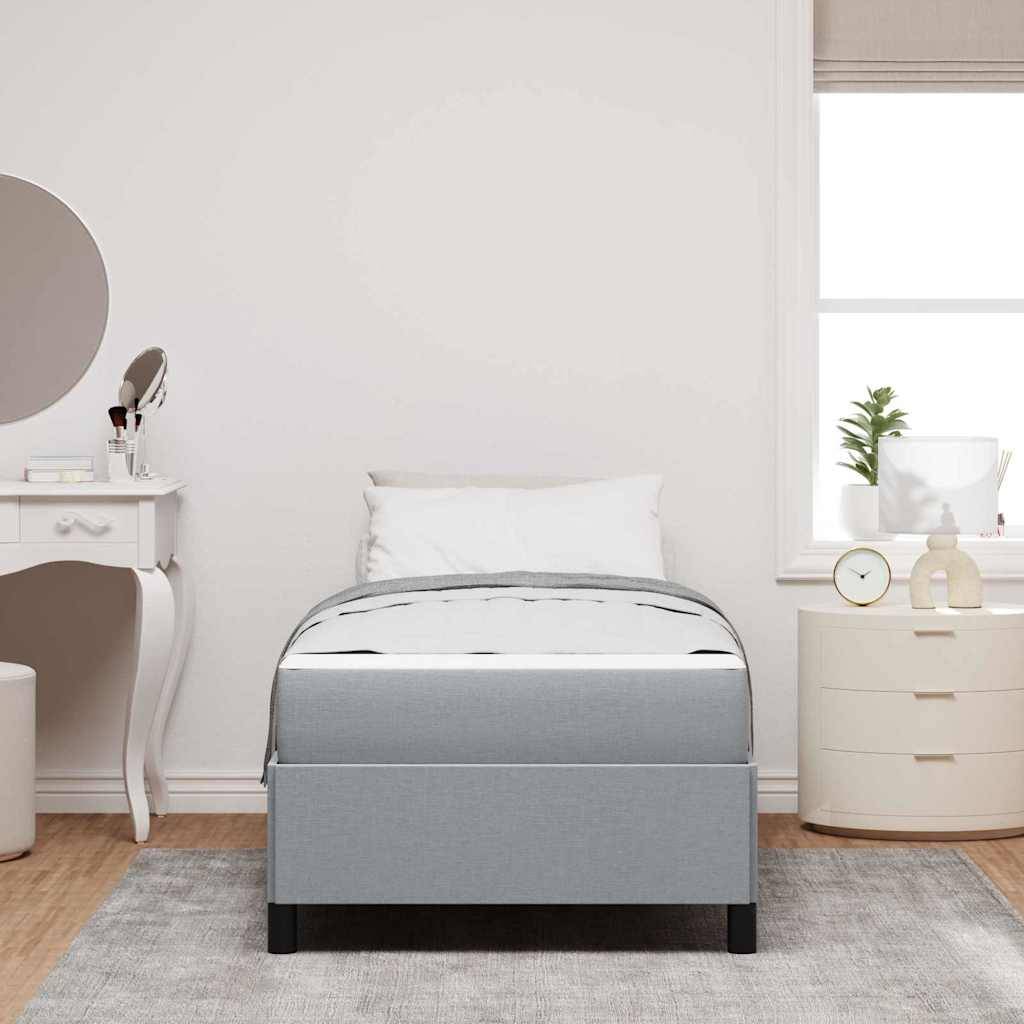 Ein ordentlich eingerichtetes Schlafzimmer zeigt ein graues Einzelbett, einen runden Spiegel über einer Toilettentisch mit Beautyprodukten auf der linken Seite und ein Fenster mit Pflanzen auf der rechten Seite.