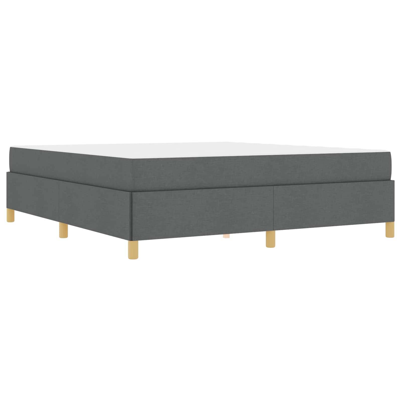 Ein grau gepolsterter Bettrahmen mit Holzbeinen, von einer schrägen Seitenansicht gezeigt.