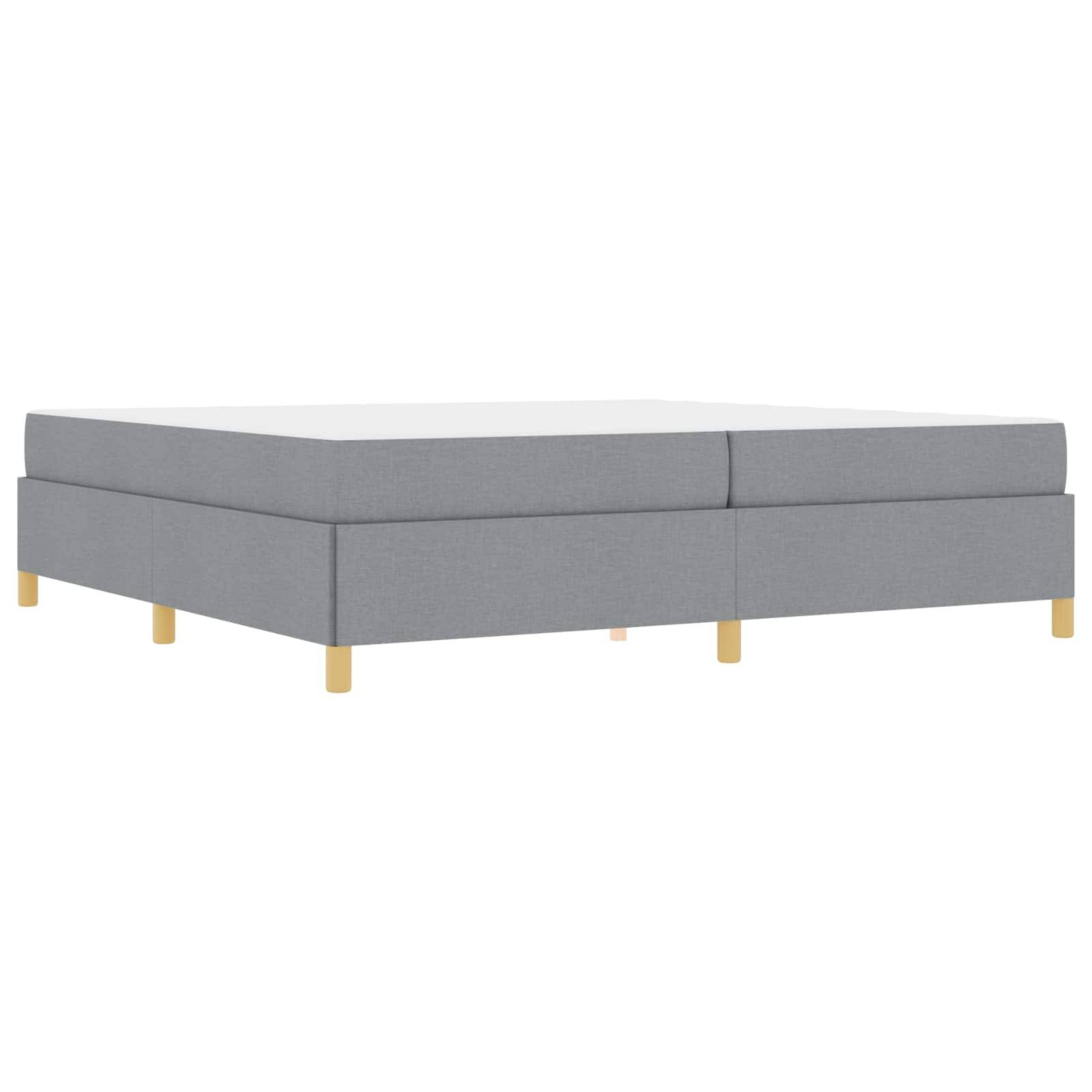 Ein grauer, minimalistischer Polsterbettrahmen mit hellen Holzbeinen, horizontal positioniert, vor einem schlichten weißen Hintergrund.