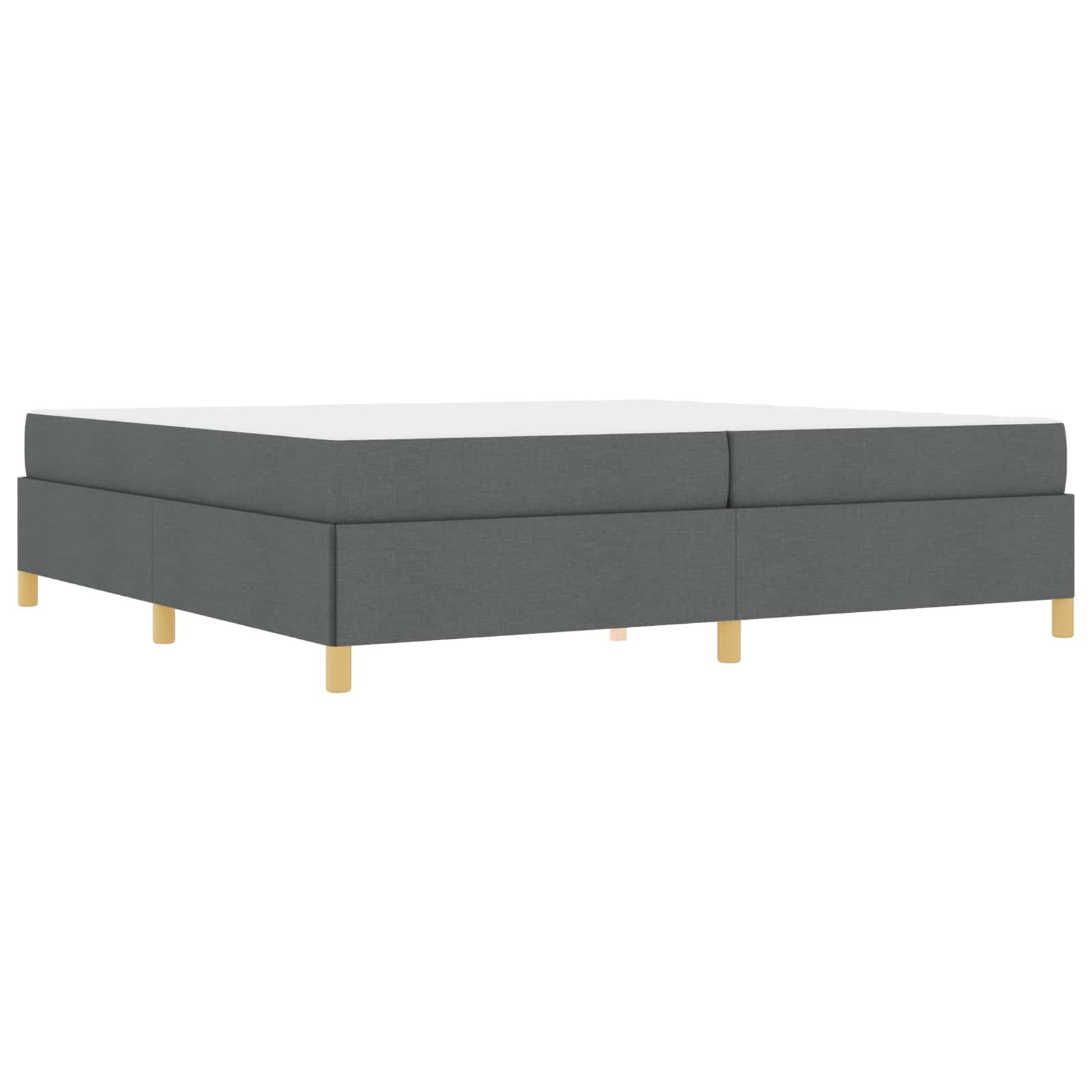 Eine flache graue gepolsterte Bettuntergestell mit hellen Holzbeinen, das ein einfaches und modernes Design präsentiert, das sich für verschiedene Innenräume eignet.
