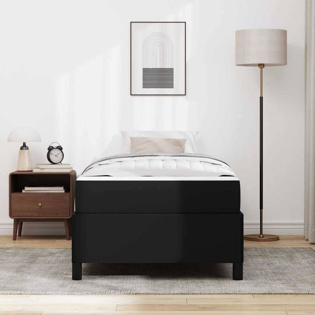 Minimalistisches Schlafzimmer mit einem schwarzen Bett, einem Nachttisch, einer Stehleuchte und gerahmter Wandkunst an einer weißen Wand.