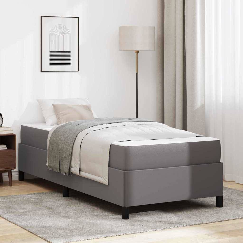 Ein minimalistisches Schlafzimmer zeigt ein modernes Plattformbett mit grauer Bettwäsche, einer hohen Stehlampe und einem gerahmten abstrakten Kunstwerk an der Wand.