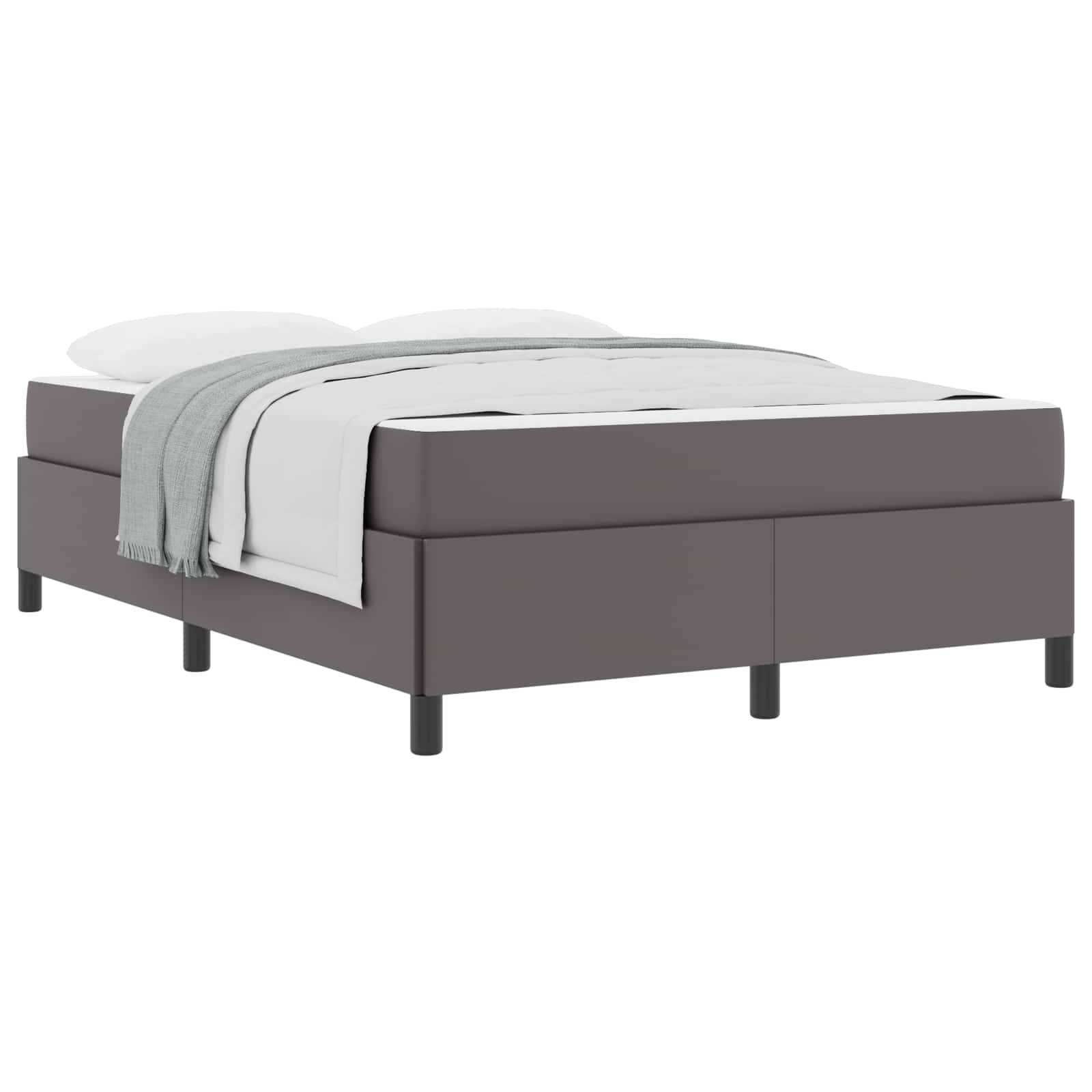 Ein modernes, flaches Bett in Grau mit weißer Bettwäsche und einer hell grauen Decke, die sorgfältig darüber ausgebreitet ist, vor einem einfarbigen Hintergrund.