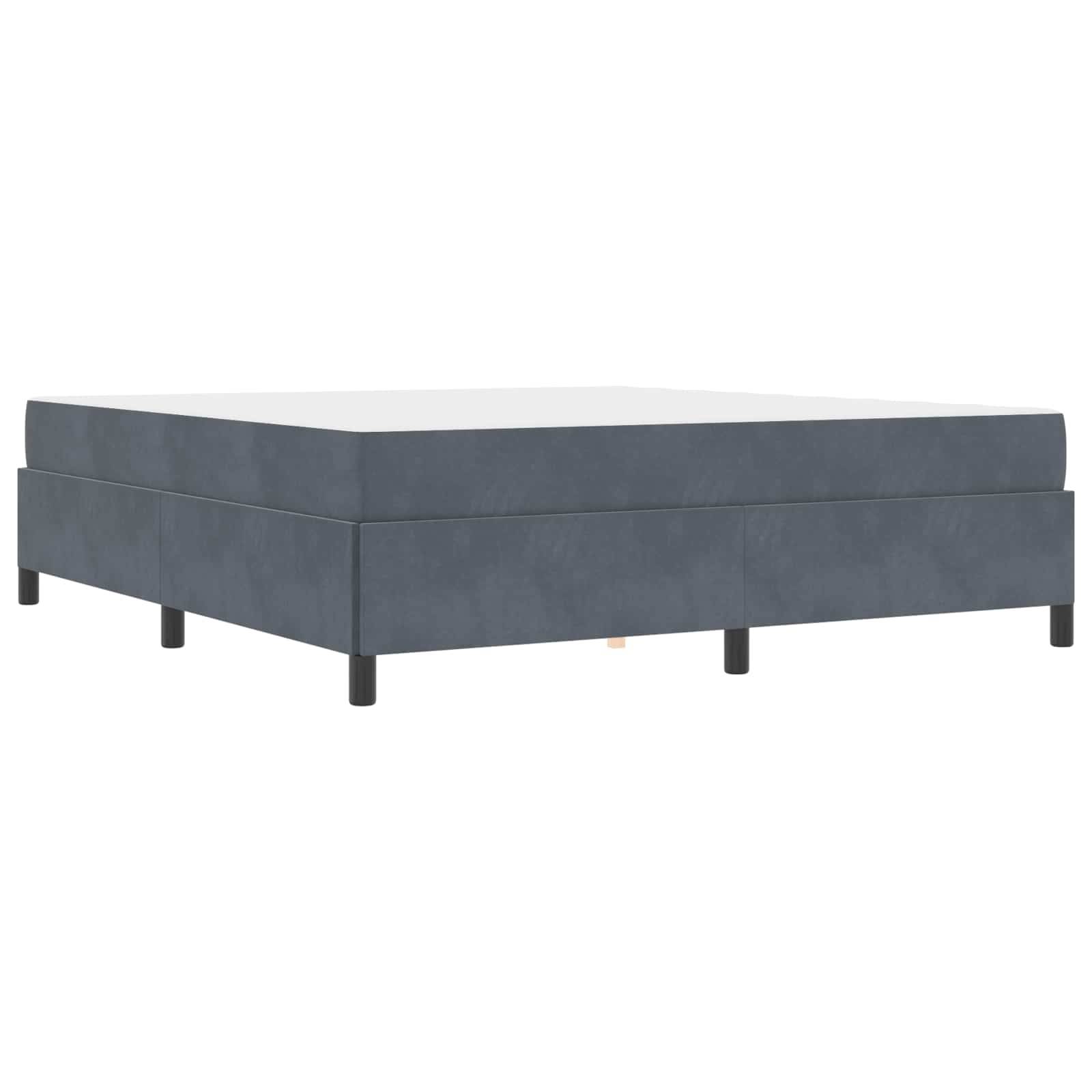 Eine dunkelgraue, mit Stoff bezogene Boxspringbettkonstruktion mit kurzen schwarzen Beinen, die ein modernes und minimalistisches Möbelstück für das Schlafzimmer darstellt.