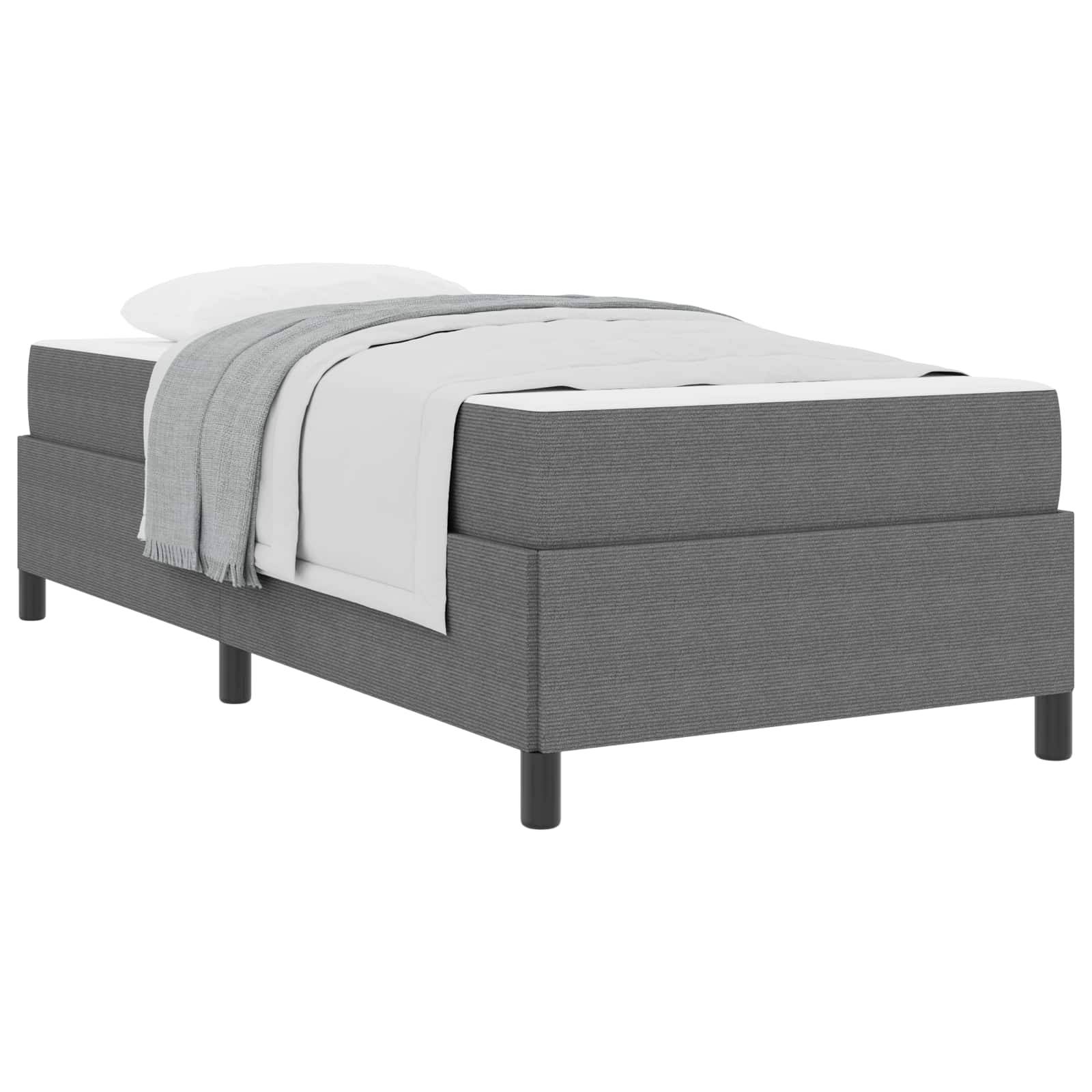 Ein grau gepolstertes Plattformbett mit einer weißen Matratze, weißer Bettdecke und einer hellgrauen Decke, die oben darauf gefaltet ist, alles auf schwarzen Beinen.