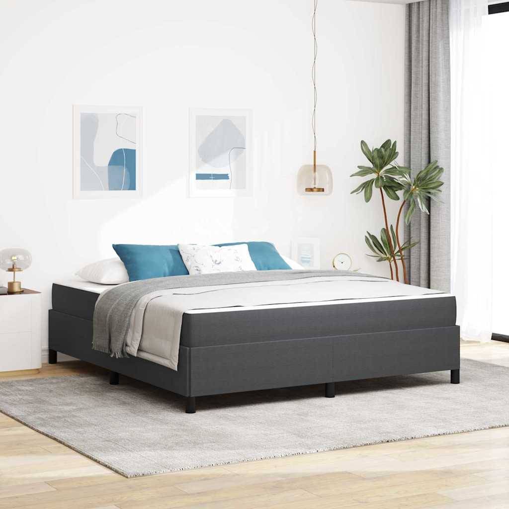 Modernes Schlafzimmer mit einem dunkelgrau gepolstertem Bett, grauer und blauer Bettwäsche, Wandkunst in Rahmen, einer Pflanze, einem Teppich und heller weißer Dekoration.