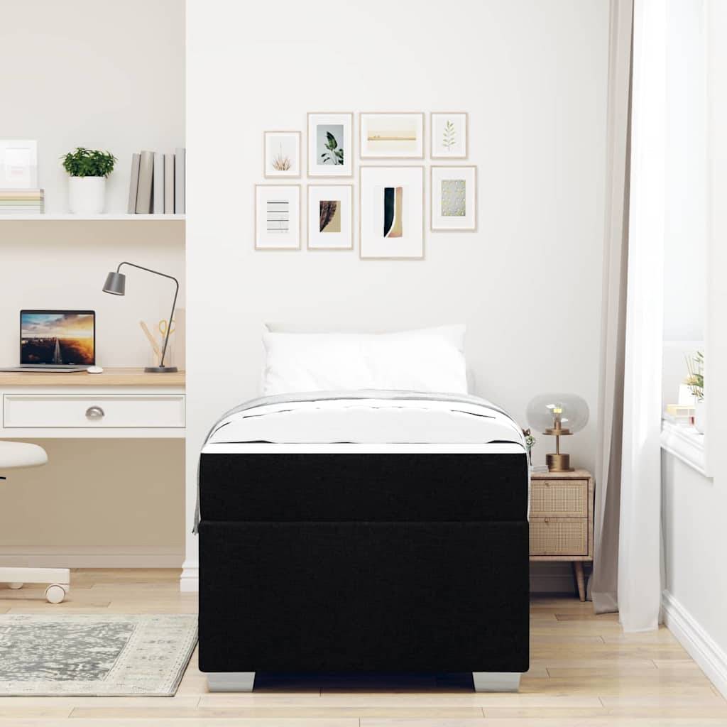 Ein modernes Schlafzimmer mit einem schwarzen Bett, einem Nachttisch mit einer Lampe und einem weißen Schreibtisch an der Wand. Wandkunst und Pflanzen ergänzen die Dekoration.