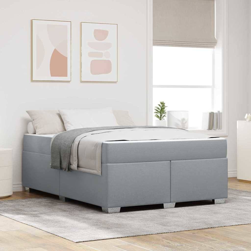 Ein modernes Schlafzimmer zeigt ein hellgraues gepolstertes Bett mit weißer Bettwäsche und einem grauen Überwurf, das auf einem grauen Teppich steht. Zwei abstrakte Gemälde hängen an der Wand.