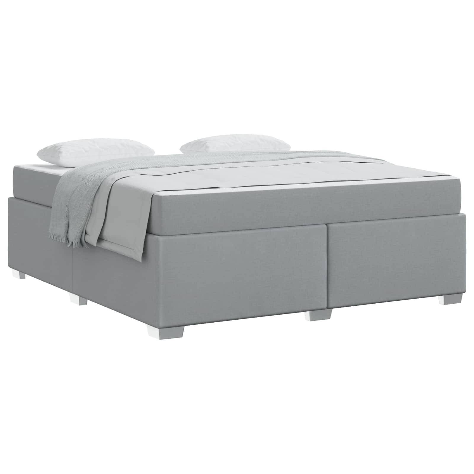 Ein minimalistisches graues Bett mit einer leichten Bettdecke und zwei Kissen, was eine moderne und schlichte Schlafzimmereinrichtung andeutet.