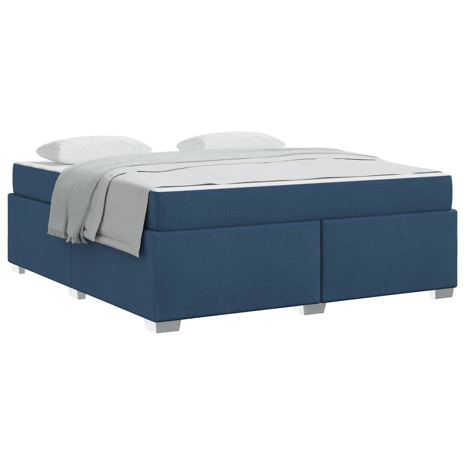 Blaupolsteriertes Bett mit weißer Bettwäsche und zwei großen Kissen oben drauf.