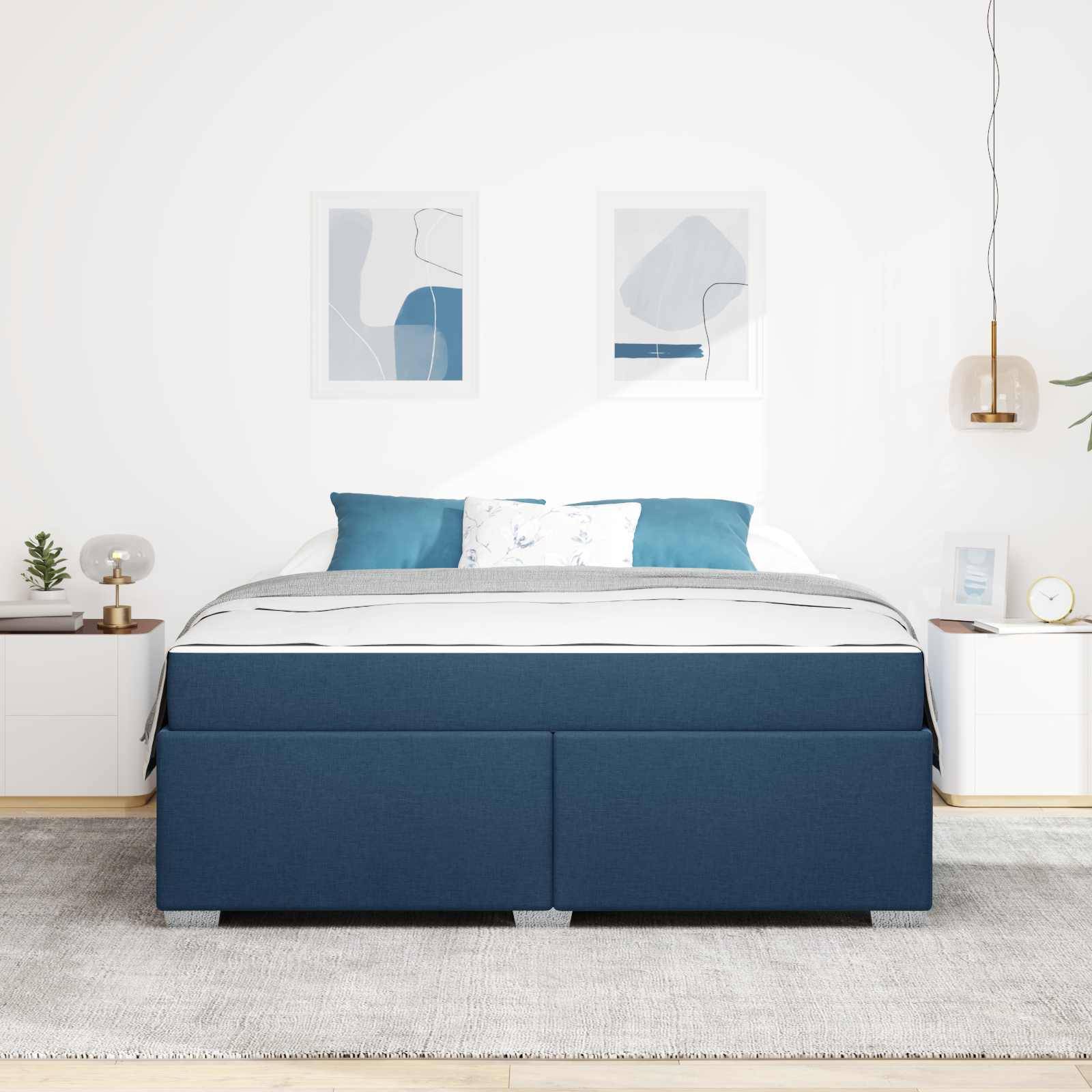 Ein modernes Schlafzimmer mit einem blau gepolsterten Bett, weißer Bettwäsche, zwei weißen Nachttischen, abstrakter Kunst an der Wand und minimalistischer Einrichtung.