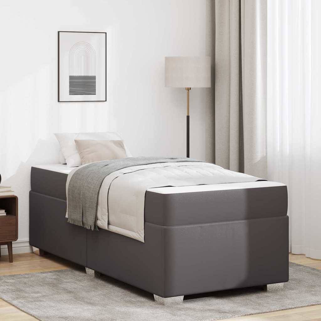 Ein modernes Schlafzimmer mit einem grauen Bett, weißer Bettwäsche, Kissen und einer grauen Decke. Eine Stehlampe und abstrakte Kunstwerke ergänzen die Dekoration.