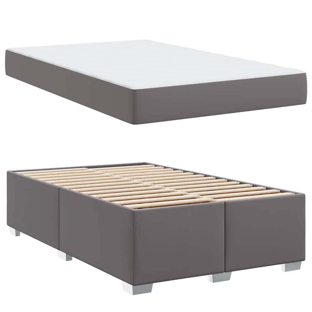 Ein grau gepolsterter Bettrahmen mit sichtbaren Holzlatten, gezeigt mit einer weißen Matratze obenauf, wobei die Struktur und das Design des Bettes hervorgehoben werden.
