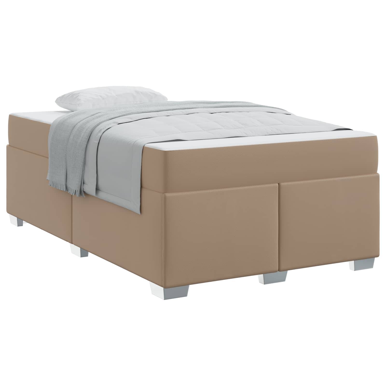Ein beige gepolstertes Bett mit einer weißen Matratze, einer hellgrauen Decke und einem Kissen, die sorgfältig darauf angeordnet sind, vor einem schlichten Hintergrund.