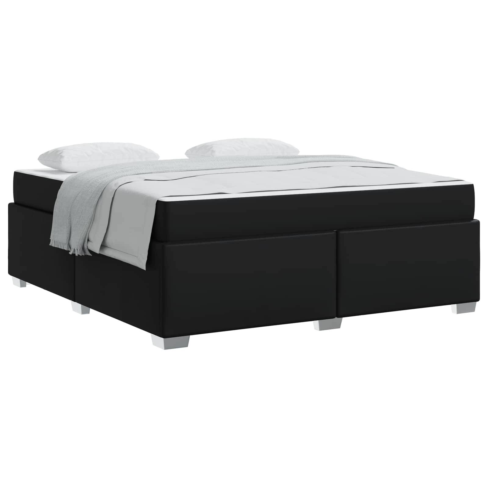 Ein schwarzer Boxspringbett mit einer weißen Matratze und Kissen, bedeckt von einer hellgrauen Decke, vor einem weißen Hintergrund.