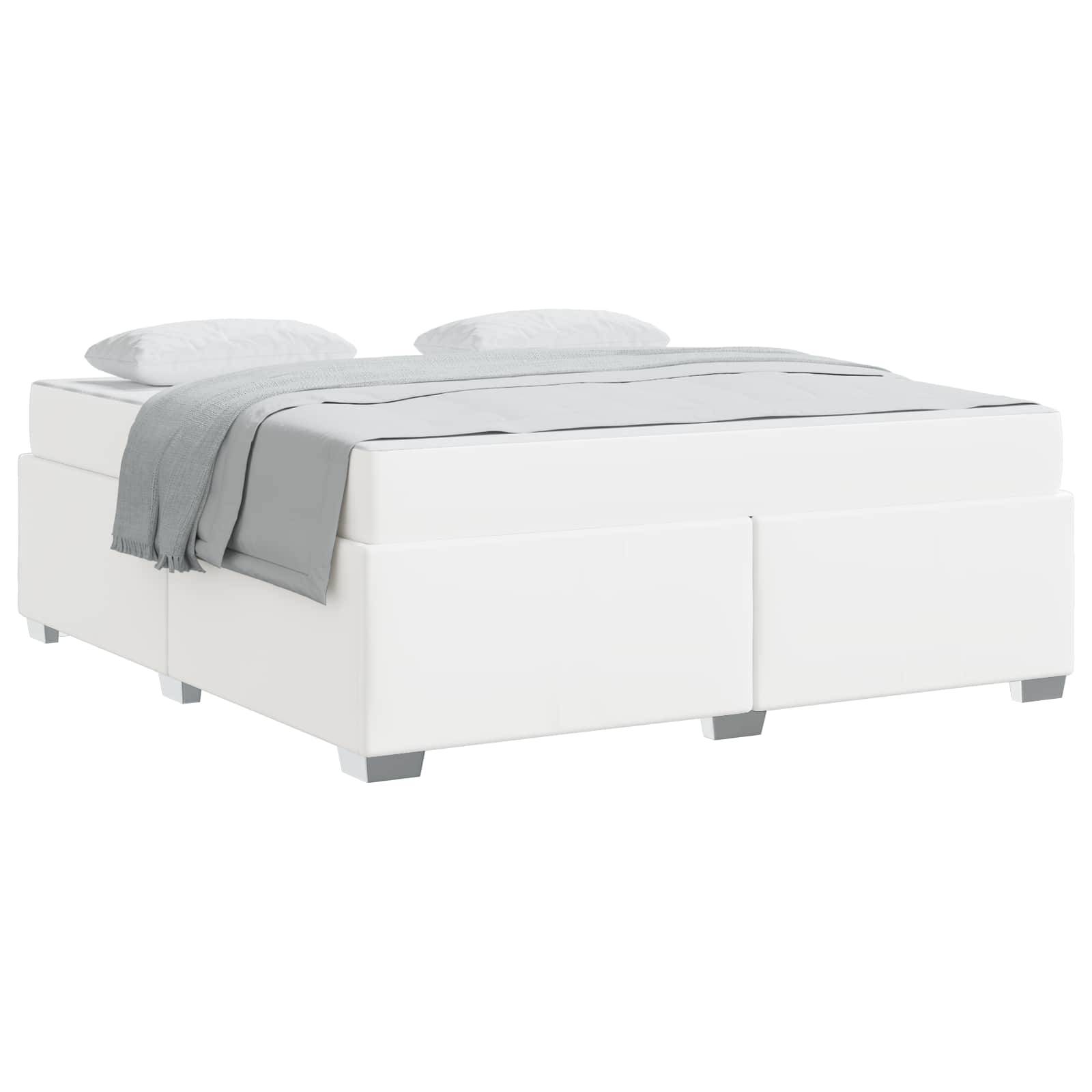 Ein modernes weißes Bett mit einer hellgrauen Decke und zwei Kissen, von der Seite betrachtet.