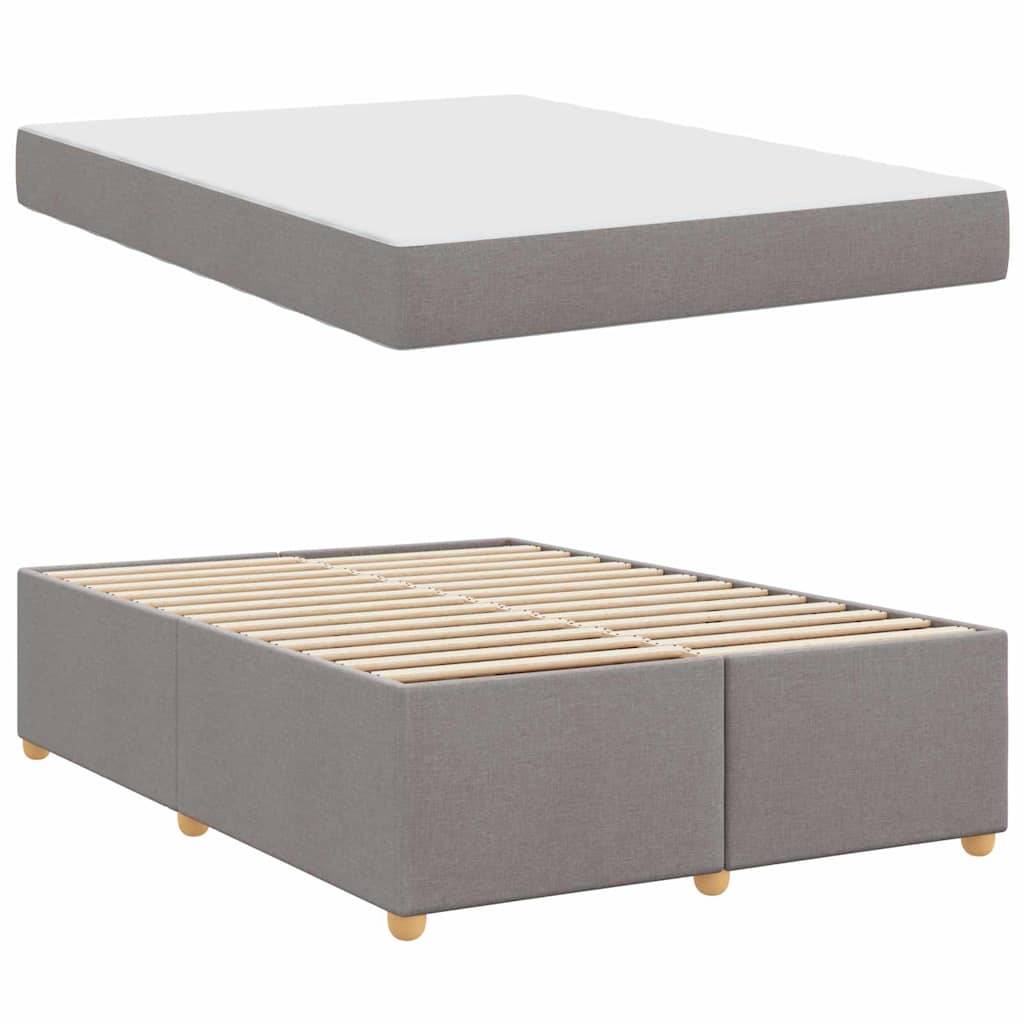 Graues gepolstertes Bettgestell mit Holzlatten und passender flacher Matratze. Das Gestell hat runde Holzbeine.