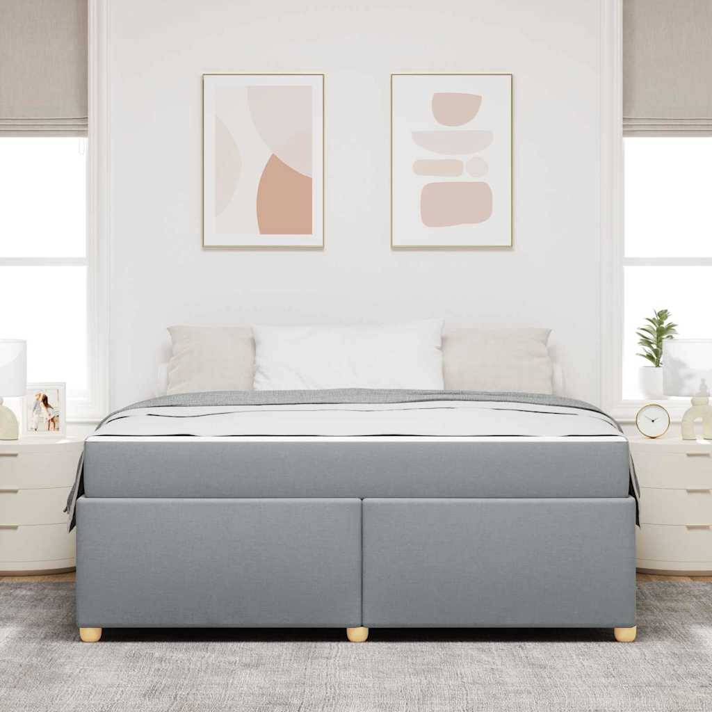 Ein modernes Schlafzimmer zeigt ein großes graues Bett mit weißer Bettwäsche, flankiert von hellfarbenen Nachttischen, auf denen jeweils eine Lampe und dekorative Gegenstände stehen.