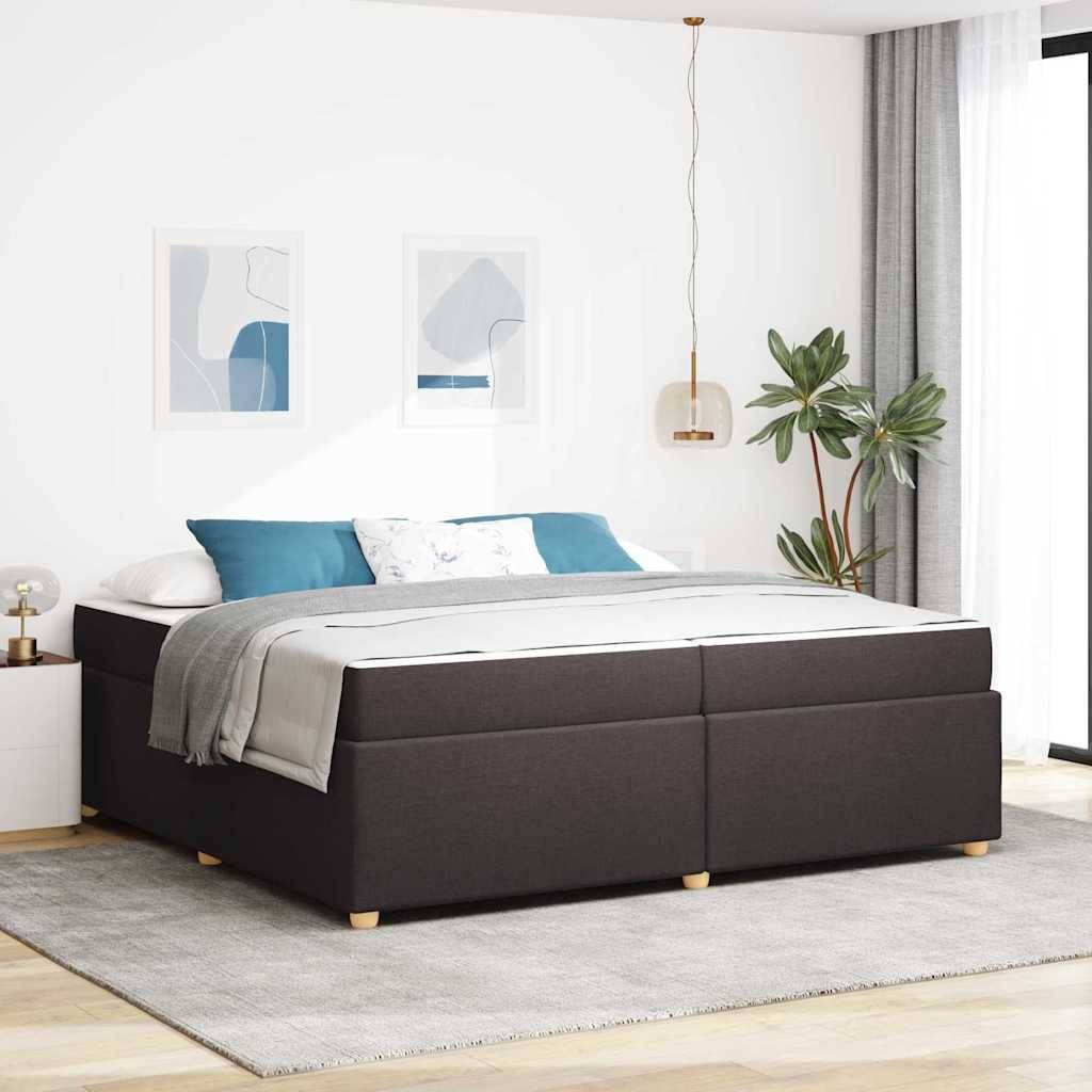 Modernes Schlafzimmer mit dunklem gepolstertem Bett, grauer Bettwäsche und blauen Kissen, Wandkunst in Rahmen, Pendelleuchte und Topfpflanze neben einem hellen Fenster.
