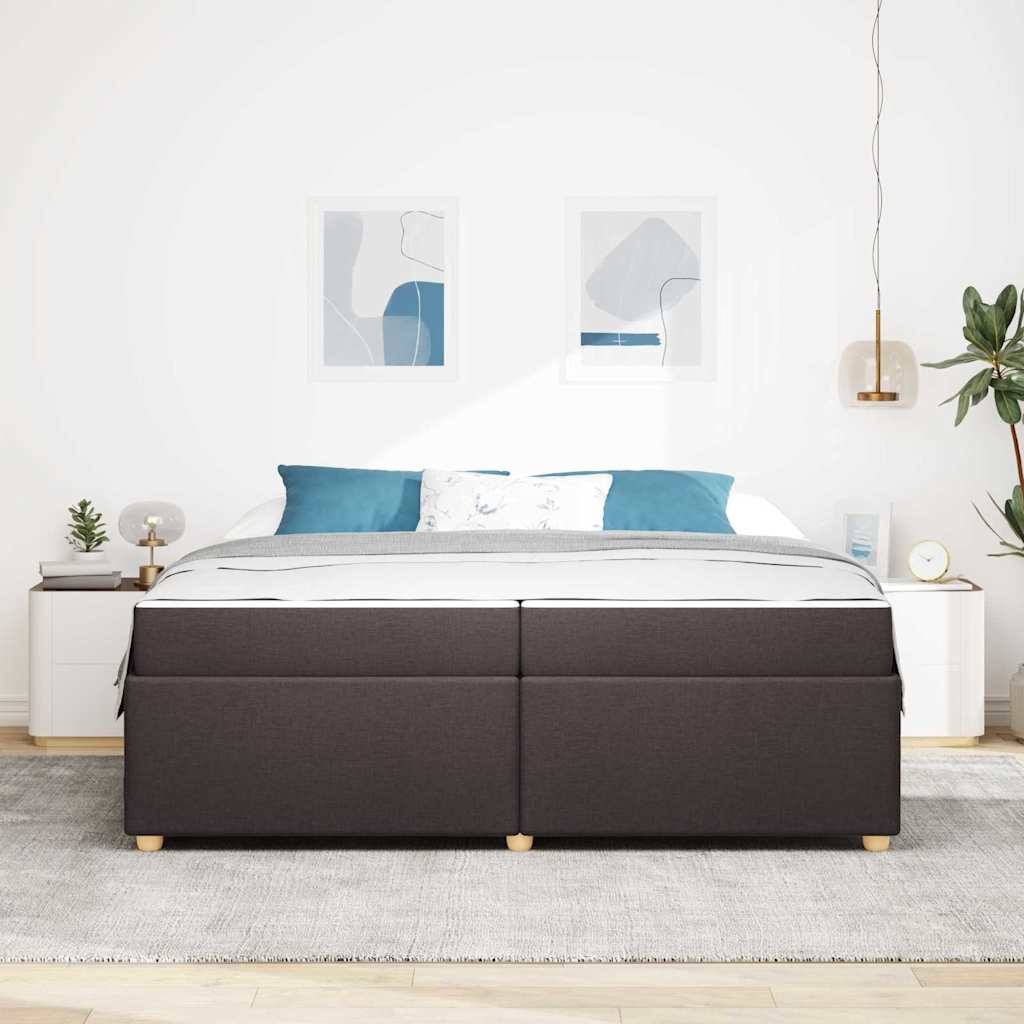 Ein ordentlich gemachtes Bett mit einer dunkel gepolsterten Basis, weißer Bettwäsche und blauen Kissen in einem hellen minimalistischen Schlafzimmer mit gerahmter Wandkunst und Nachttischen.