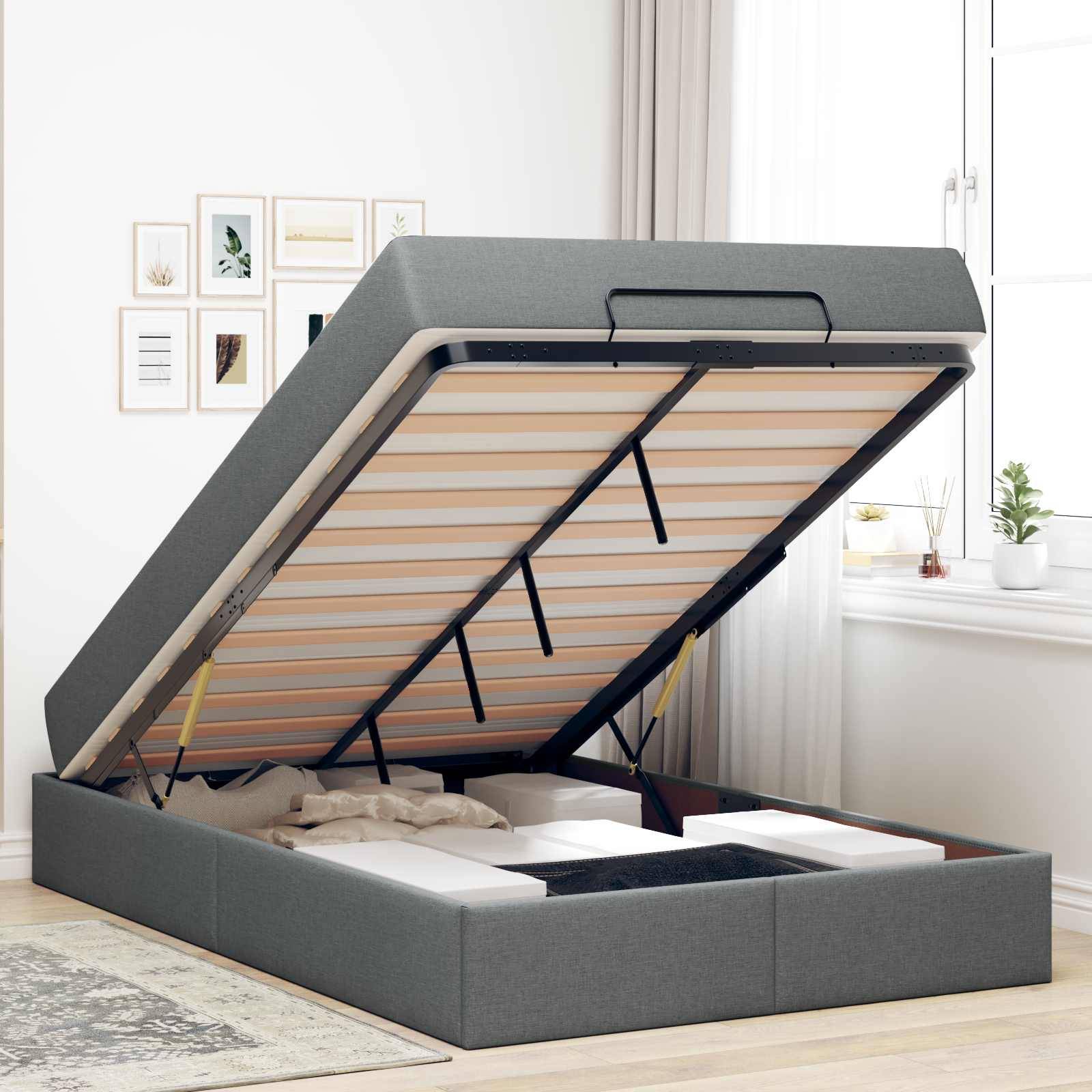 Ein Bett mit angehobenem Matratzenbereich offenbart Stauraum darunter. Der Raum verfügt über helle Wände, gerahmte Kunstwerke und ein großes Fenster mit Pflanzen.