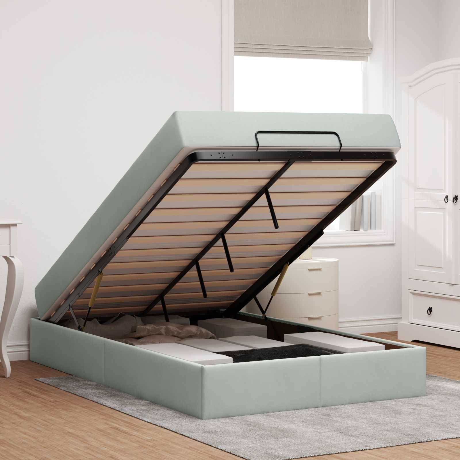 Schlafzimmer mit einem hellgrauen Ottomanen-Speicherbett, das teilweise offen ist und den Stauraum darunter zeigt. Das Zimmer verfügt über Holzbodenbelag und weiße Möbel.