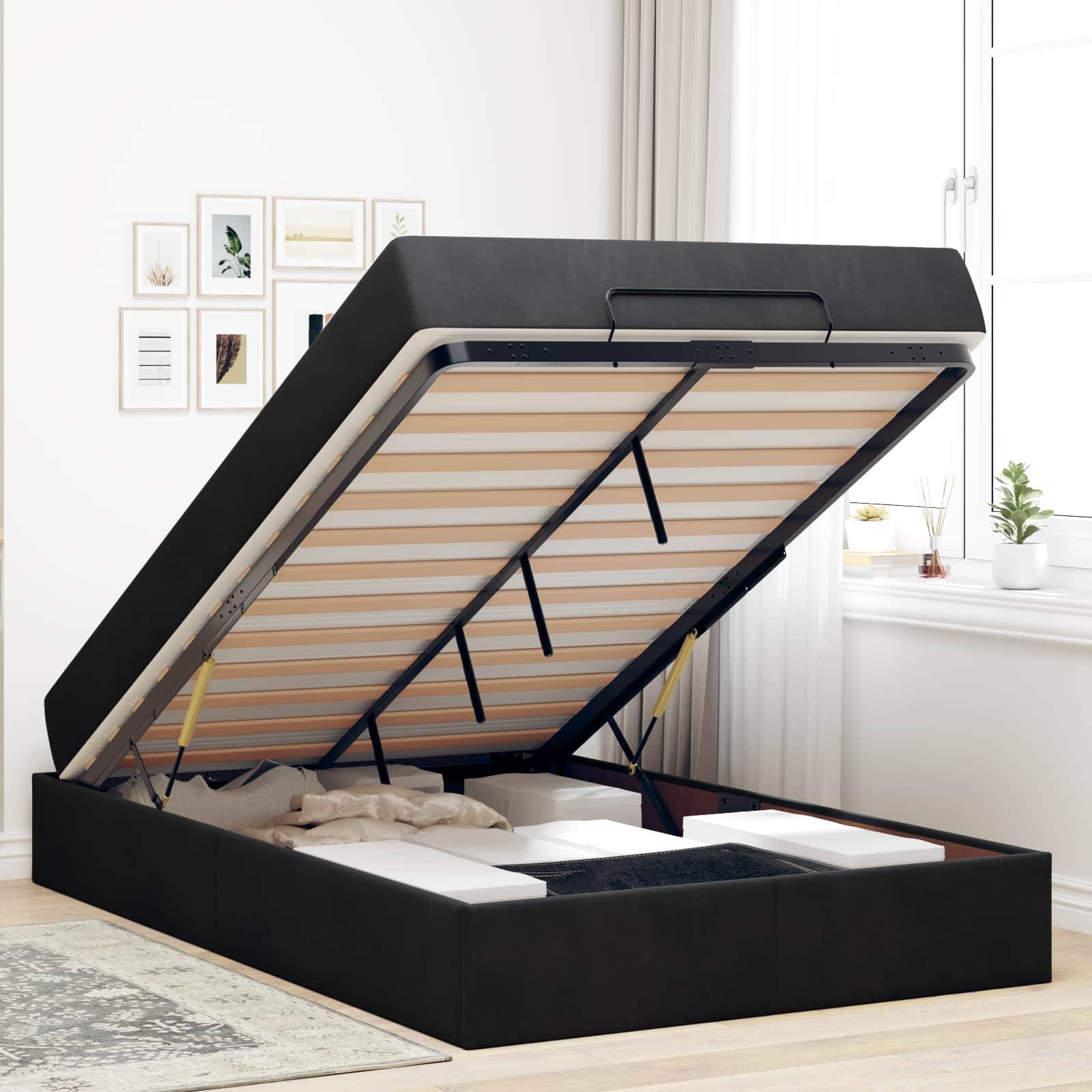 Ein schwarzes gepolstertes Bett mit einer angehobenen Matratze, die den Stauraum unter dem Bett offenbart. Gerahmte Kunstwerke schmücken die Wand, und ein Fenster mit Pflanzen befindet sich auf der rechten Seite.