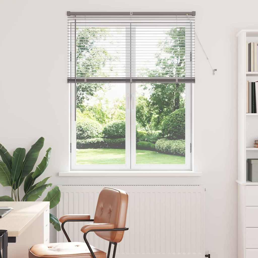 Ein heller Raum mit einem Schreibtisch und einem Stuhl, die zu einem großen Fenster ausgerichtet sind, das auf einen grünen Garten blickt. Zimmerpflanzen und ein weißes Bücherregal dienen als Dekoration.