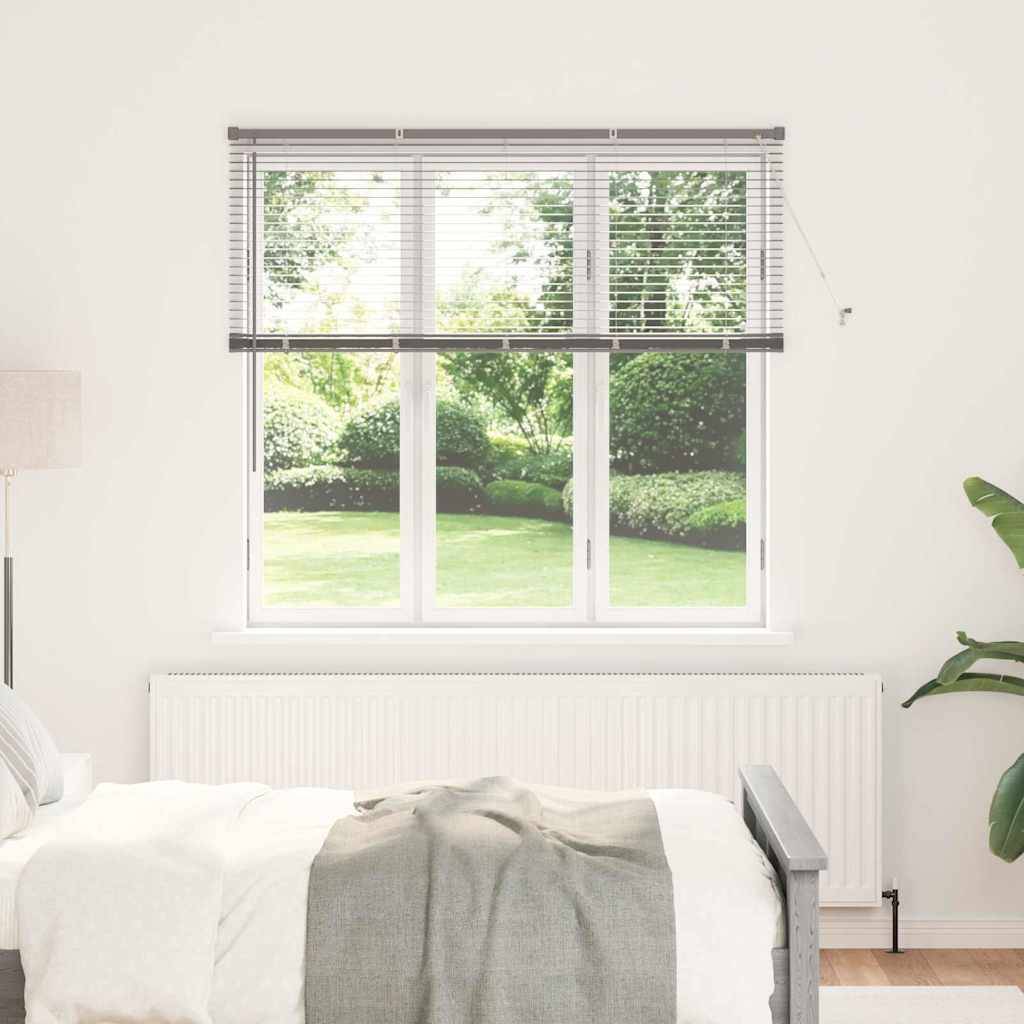 Ein helles Schlafzimmer mit einem großen Fenster, das einen grünen Garten zeigt. Das Bett hat weiße Bettwäsche, und unter dem Fenster befindet sich ein Heizkörper.