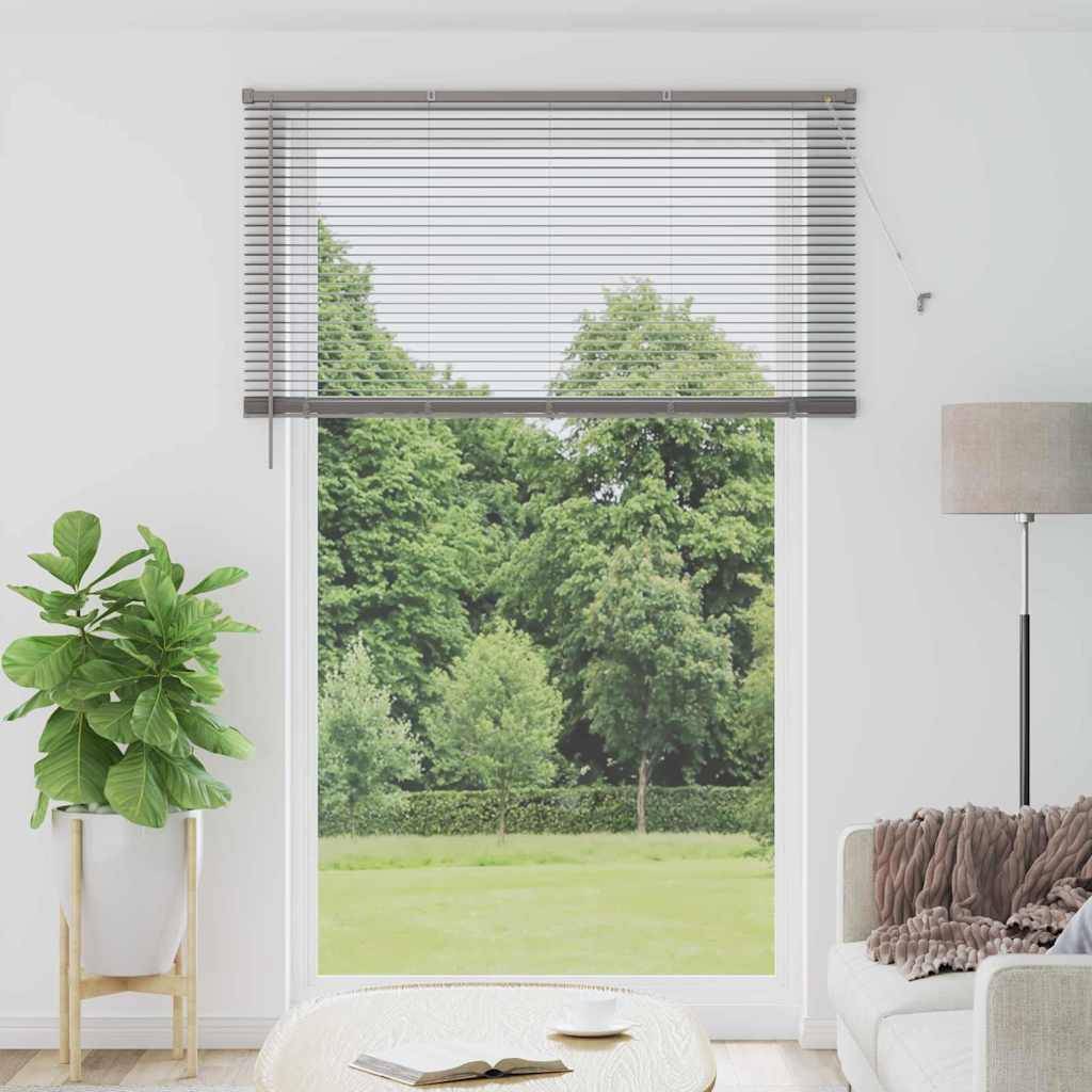 Ein Fenster mit geschlossenen Jalousien blickt auf Grünflächen. Innen eine gemütliche Ecke mit einer Topfpflanze, einer Stehlampe und einem Sofa mit Kissen.