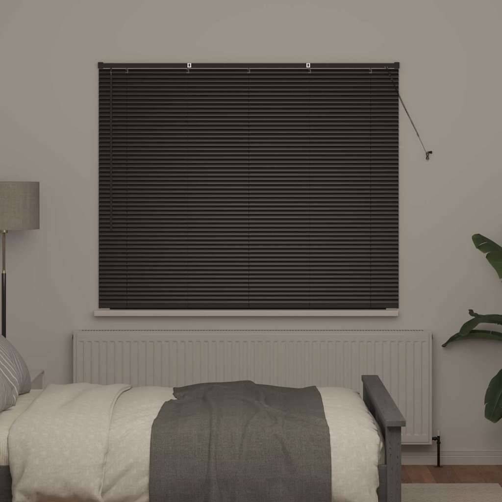 Ein Schlafzimmer mit einem ordentlich gemachten Bett mit grauen Bettwaren, einer Lampe auf dem Nachttisch und einem Fenster, das von dunklen Jalousien verdeckt wird.