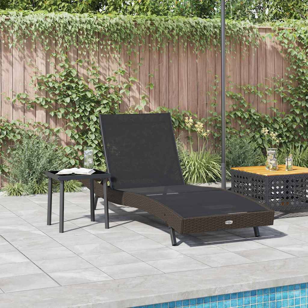 Eine Loungebereich am Pool mit einem schwarzen Korbsessel und Beistelltisch. Ein Holzzaun und üppiges Grün sorgen für eine entspannende Outdoor-Atmosphäre.