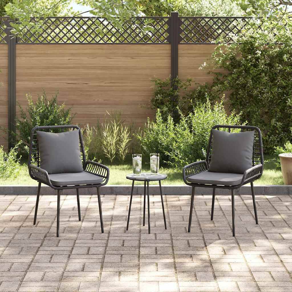 Outdoor-Terrasse mit zwei leeren Stühlen und einem kleinen Tisch, vor einem Holzzaun mit Grünpflanzen. Heller, sonniger Tag.