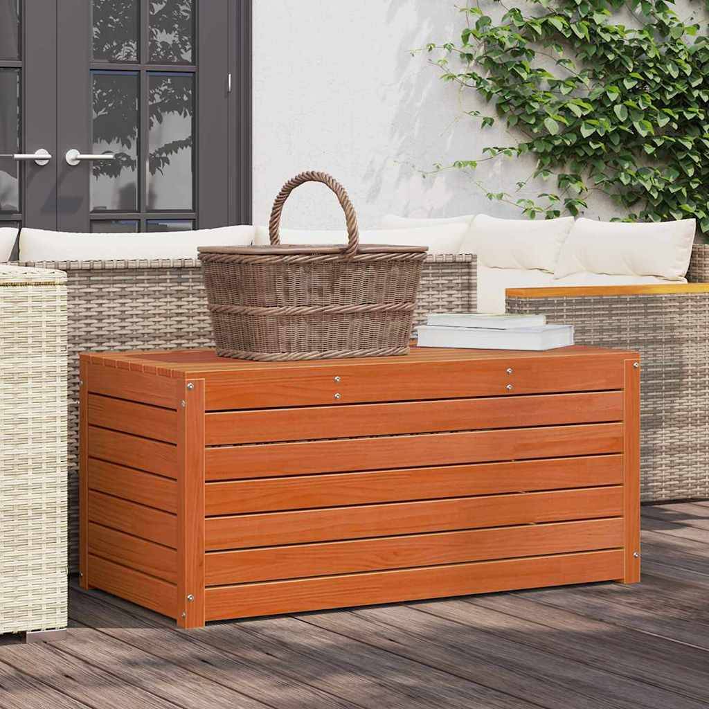 Eine Terrassenszene mit einem Flechtkorb auf einer Holzaufbewahrungsbox, umgeben von Outdoor-Sitzmöbeln und Grünpflanzen neben Glaspaneltüren.