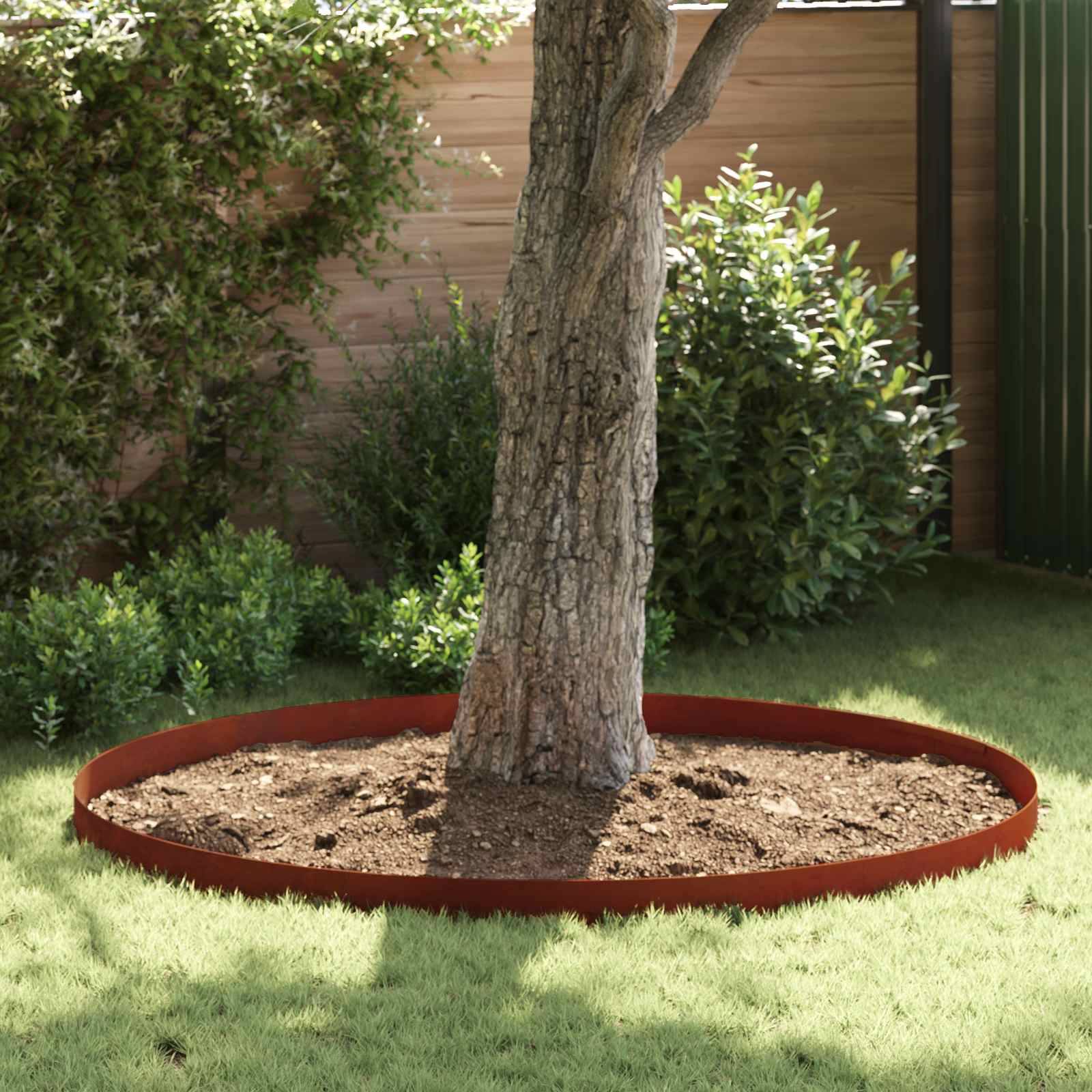 Ein rundes, mit Mulch bedecktes Blumenbeet umgibt einen Baum in einem Hinterhof, mit einem Zaun und Grünflächenim Hintergrund.