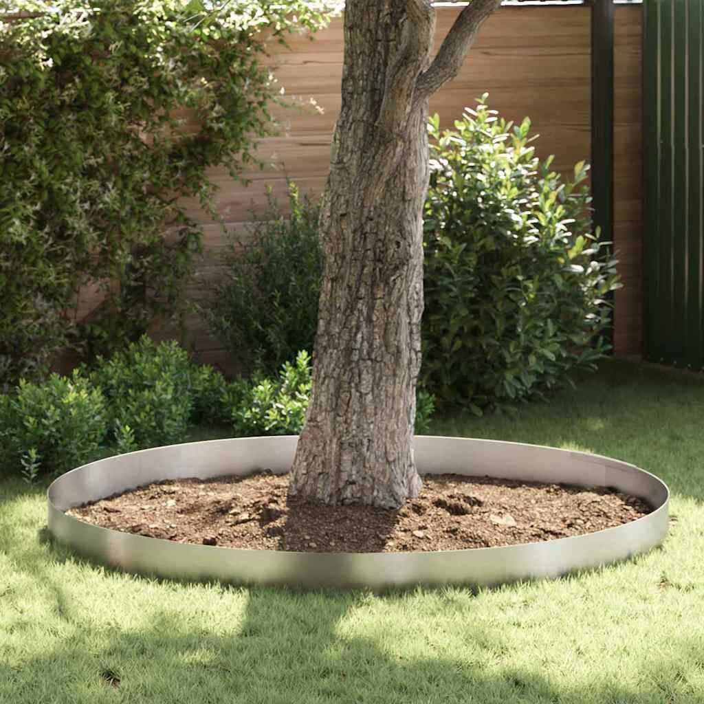 Ein junger Baum, umgeben von einer kreisförmigen Metall-Gartenumrandung, mit sauber geschnittenem Rasen und Büschen in einer eingezäunten Hinterhoflandschaft.