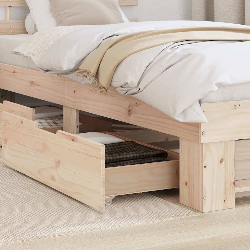 Ein Holzbett mit einer beigen Decke und weißen Kissen. Darunter öffnet sich eine Schublade und gibt Stauraum frei, in dem sich eine schwarz-weiß karierte Box befindet.