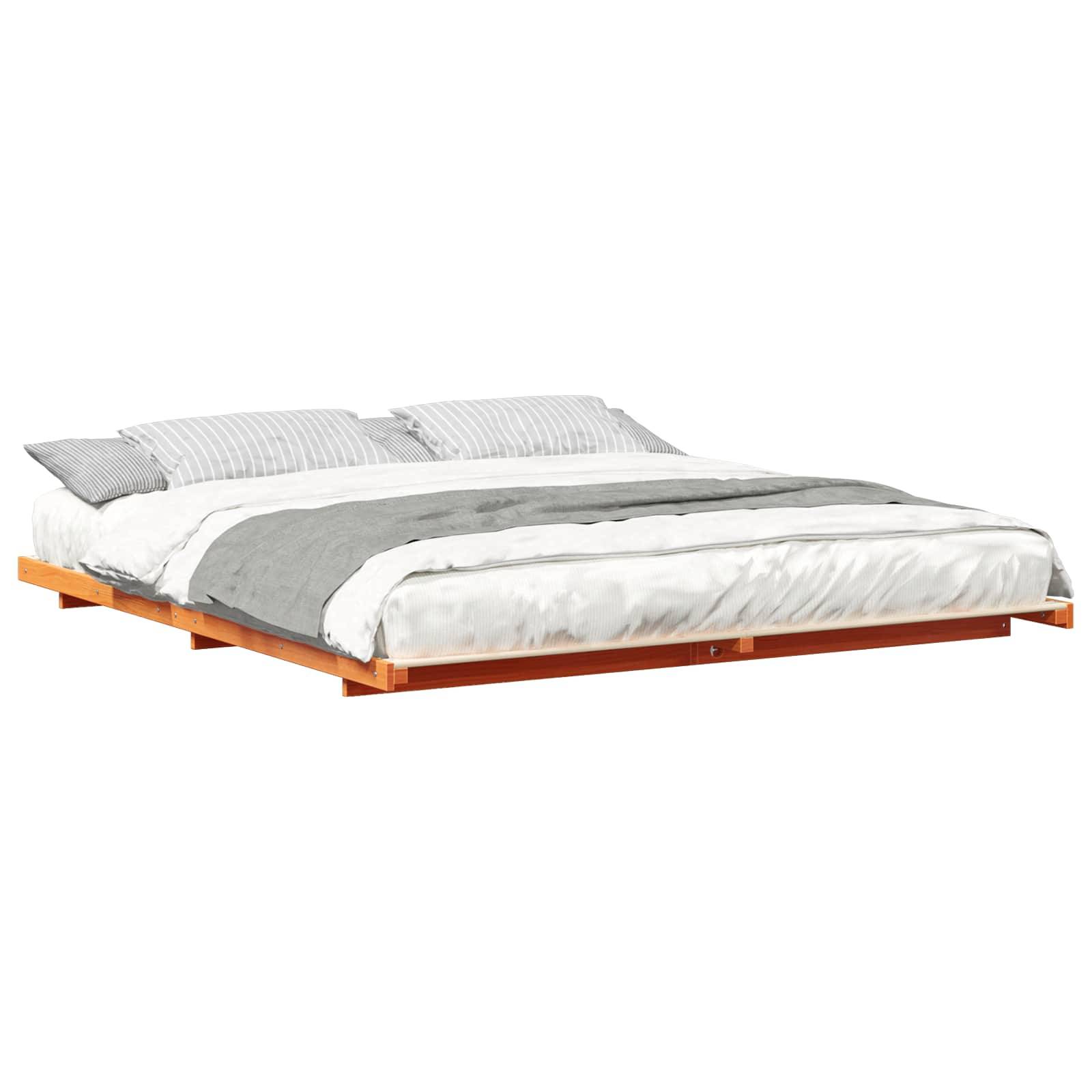 Ein modernes, niedriges Plattformbett aus Holz mit einem grauen und weißen Bettwäscheset, ausgestattet mit zwei Kissen.