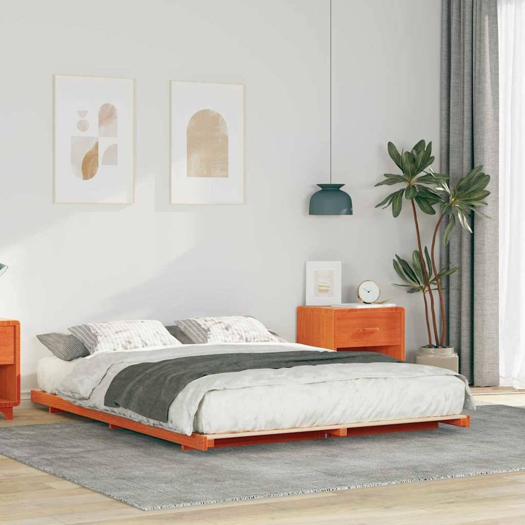 Ein modernes Schlafzimmer mit einem niedrigen Holzbett, grauer Bettdecke und beigen Kissen. Kunst an der Wand, Topfpflanze, Nachttische und eine Hängelampe sorgen für Dekoration.