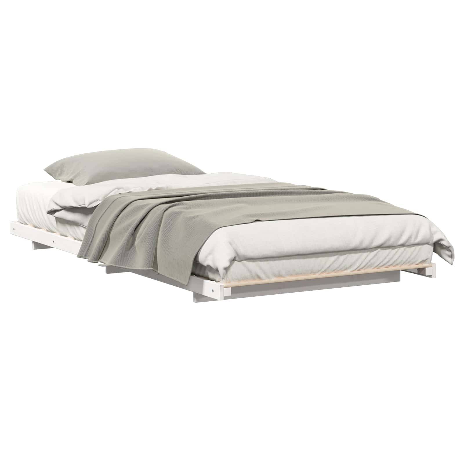 Ein minimalistisches Bett mit einem weißen Rahmen, weißer Bettwäsche und einer hellgrauen Decke. Das Bett ist ordentlich gemacht mit einem einzelnen Kissen.