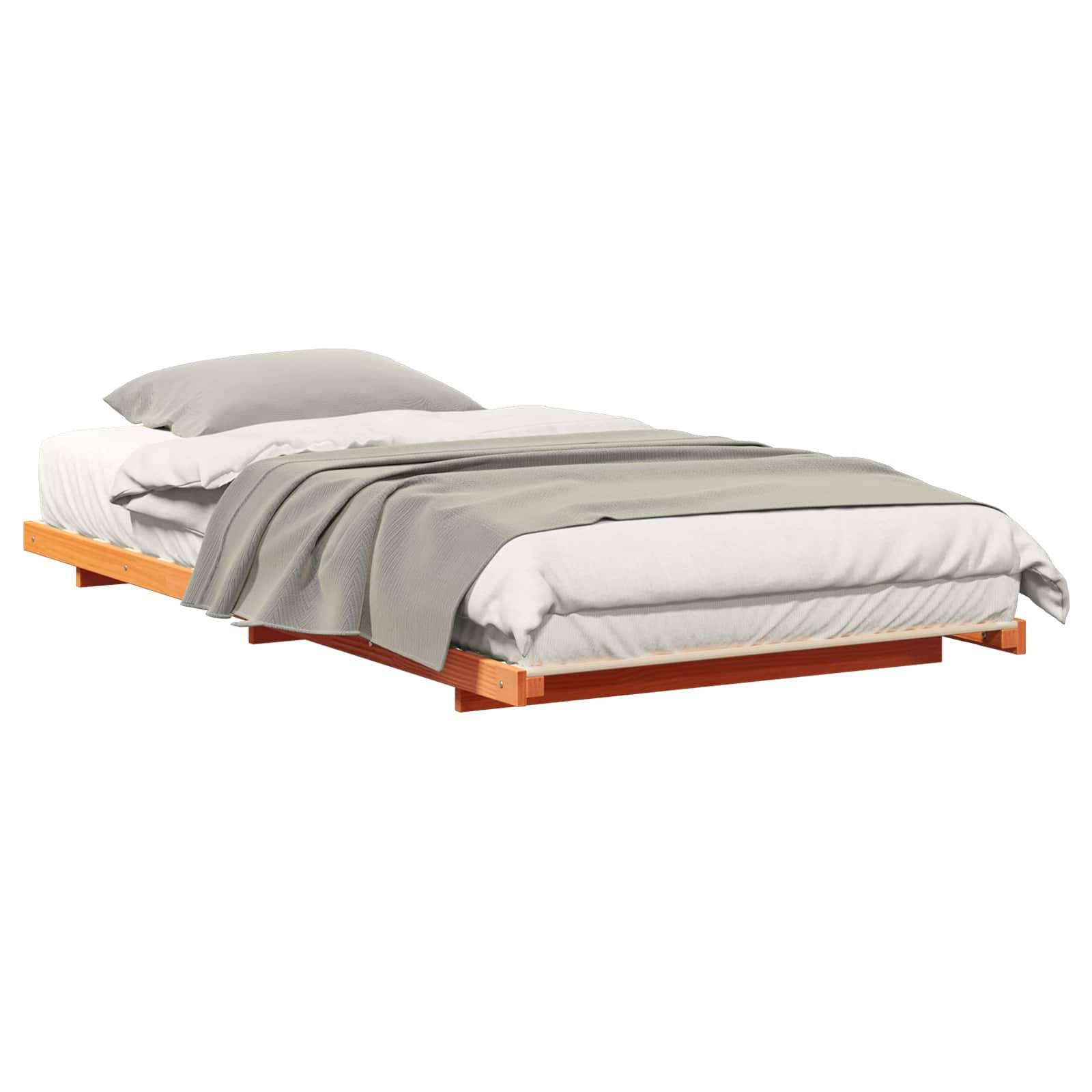 Ein niedriges Holzbett mit sorgfältig angeordneter weißer Matratze, grauer Decke und weißem Kissen, das ein minimalistisches Schlafzimmermöbeldesign präsentiert.